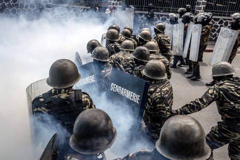 TOPSHOT - Members of the Malagasy gendarmerie take cover behind their shields amid tear gas during clashes between demonstrators and security forces in protests calling for the resignation of President Andry Rajoelina in Antananarivo, on October 11, 2025. (Photo by Luis TATO / AFP)